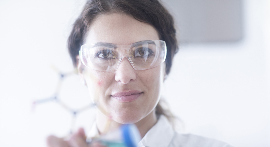 Eine Wissenschaftlerin in weißem Kittel mit Laborbrille