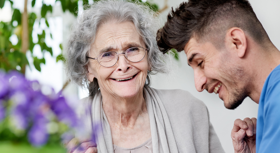 Ein Altenpfleger und eine ältere Frau unterhalten sich im Altenheim