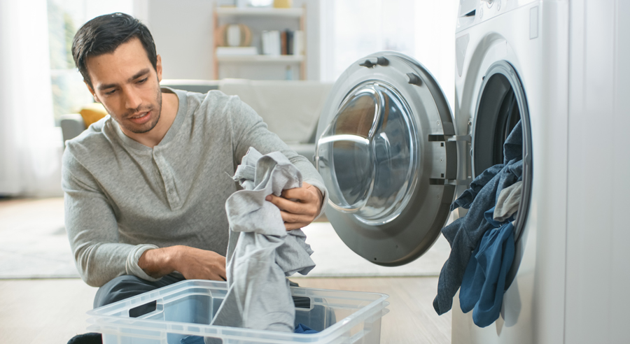 Ein Mann füllt eine Waschmaschine mit Wäsche