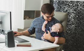 Mann mit Baby in Home-Office am Schreibtisch mit PC
