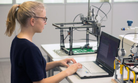 Junge Frau arbeitet in einem Labor an einem Laptop.